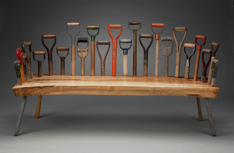 Wood bench adorned with various shovel handles on the back and sides