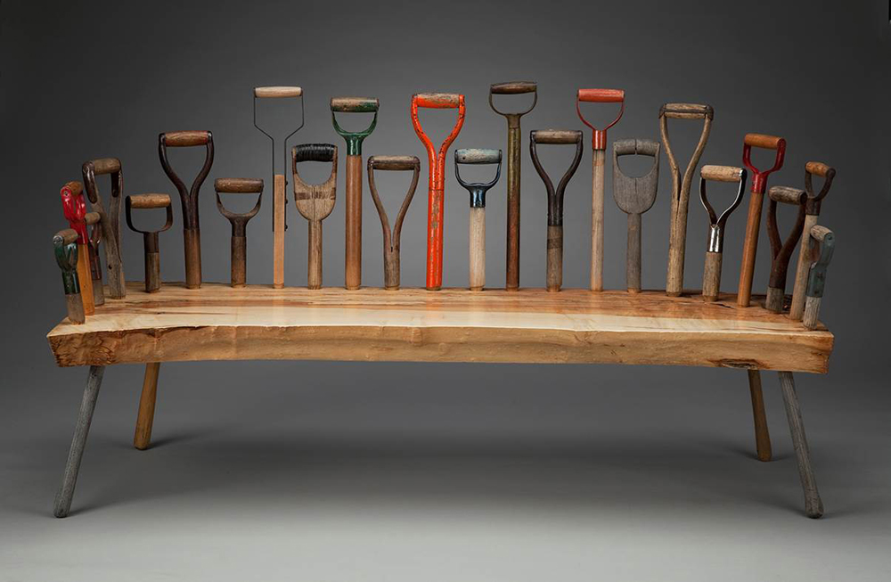 Wood bench adorned with various shovel handles on the back and sides