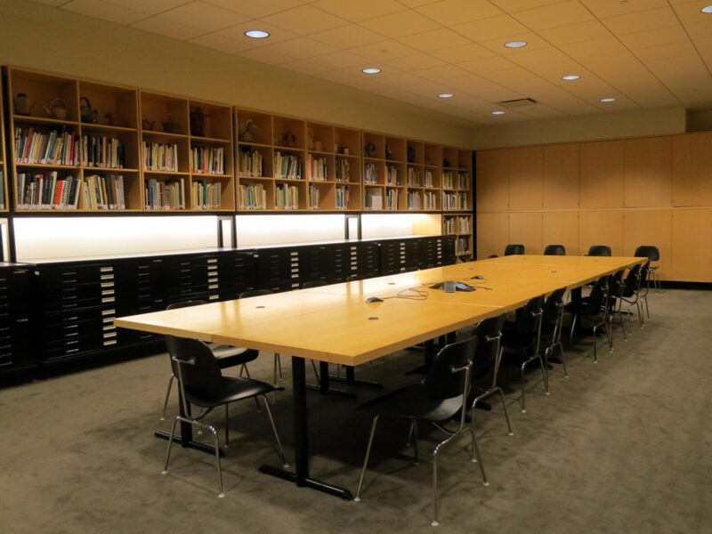 A table surrounded by bookshelves wit art records