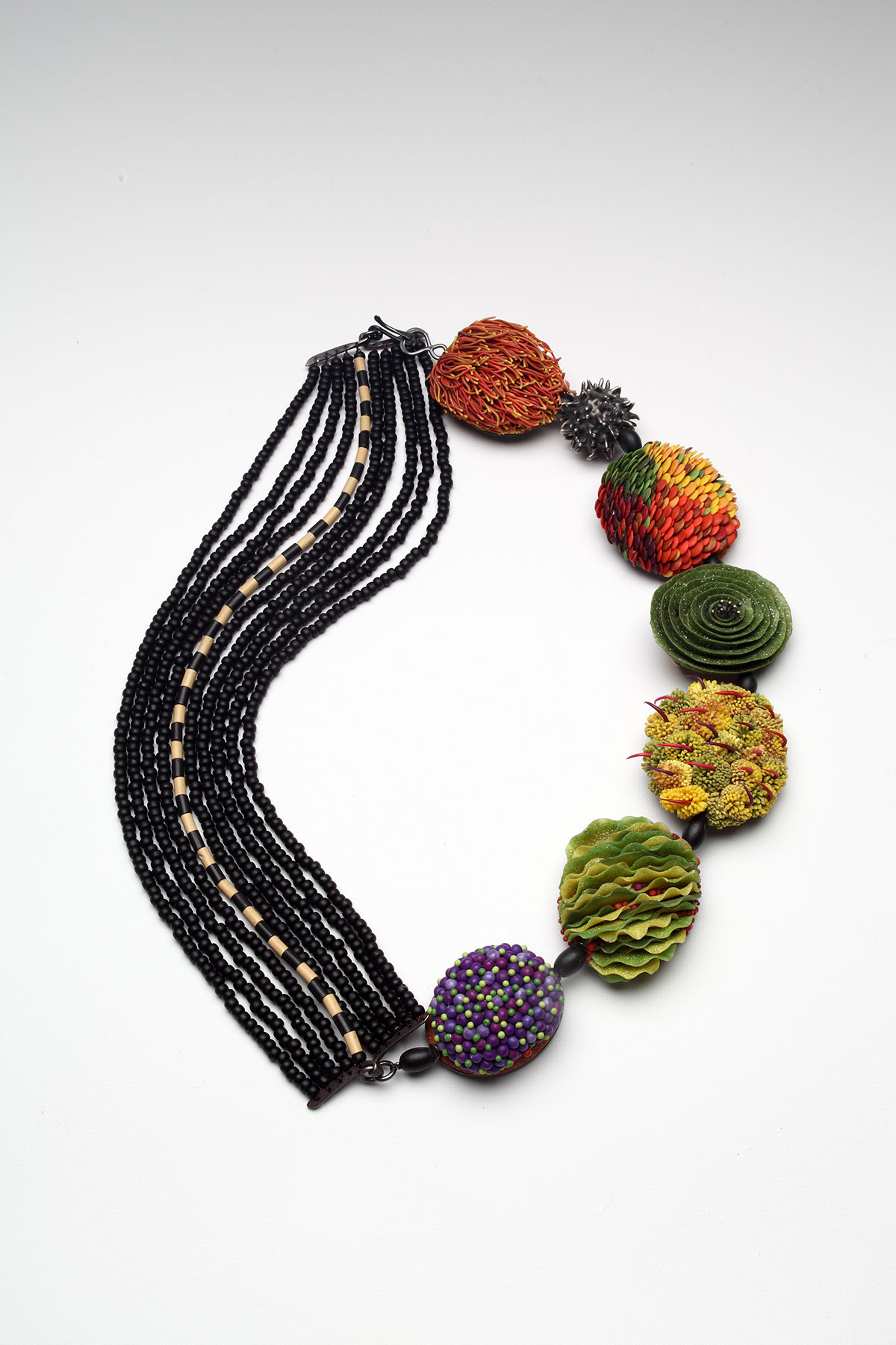 Neckpiece with strings of beads on one half and various organic shapes on the other