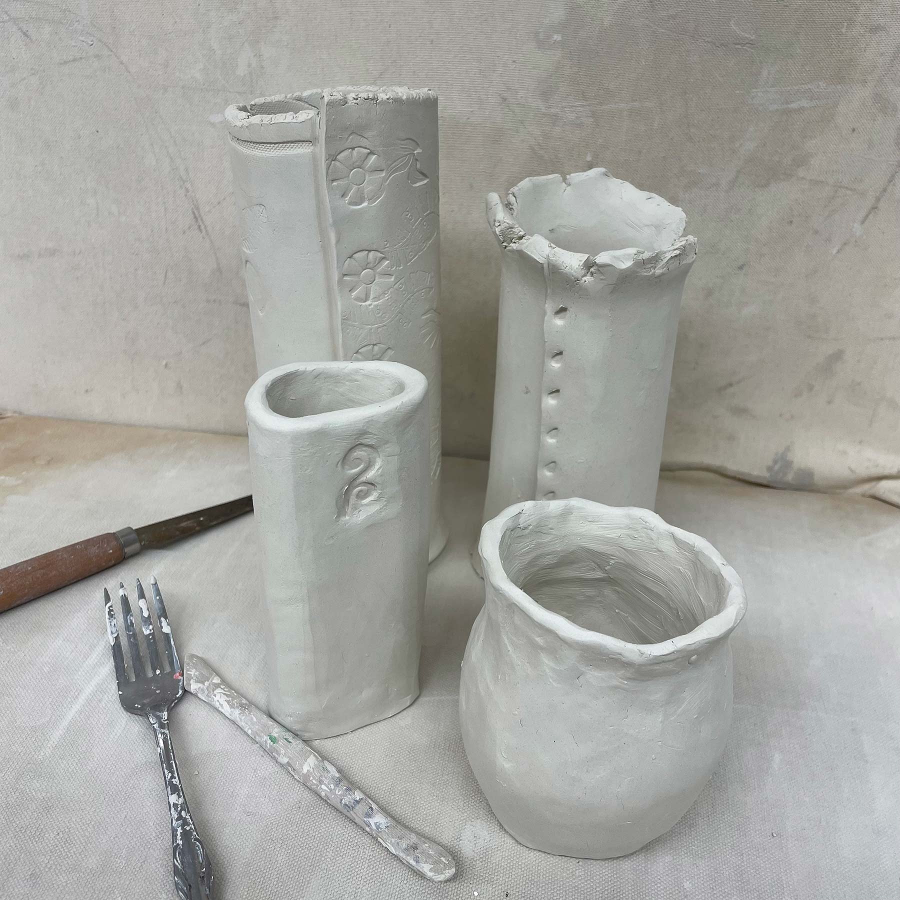 Four ceramic vases arranged from front to back in increasing size, each with a pattern inscribed into them
