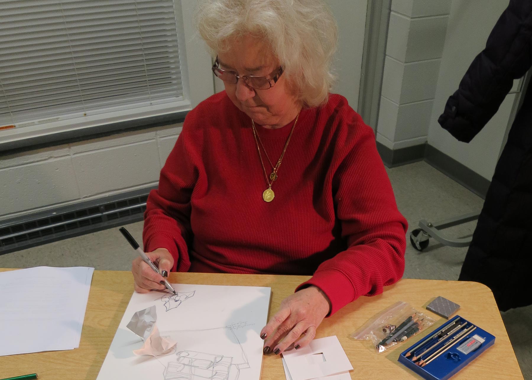 Woman in a red sweater drawing a still life