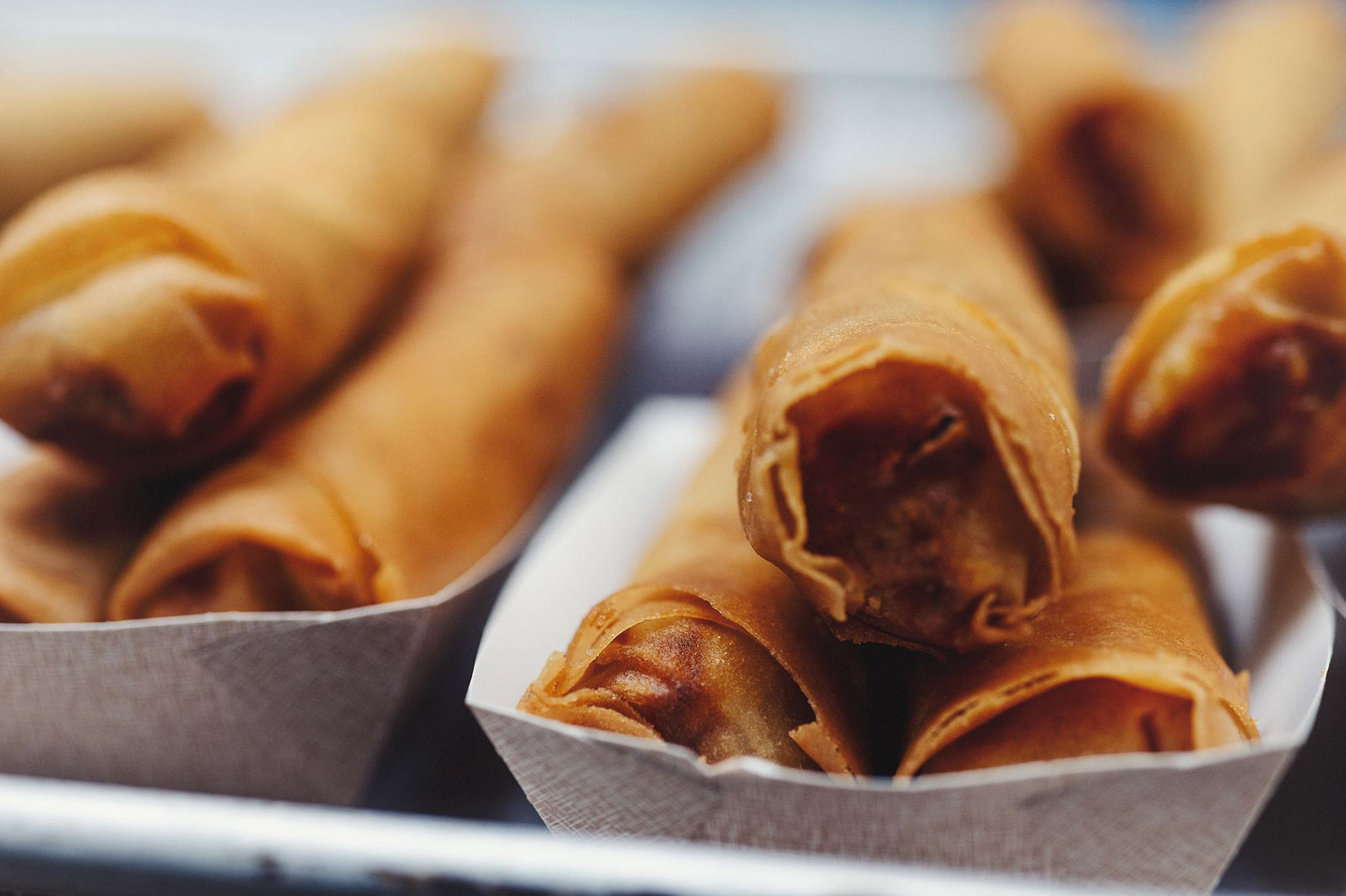 Several cartons with cooked spring rolls by Lao restaurant SapSap