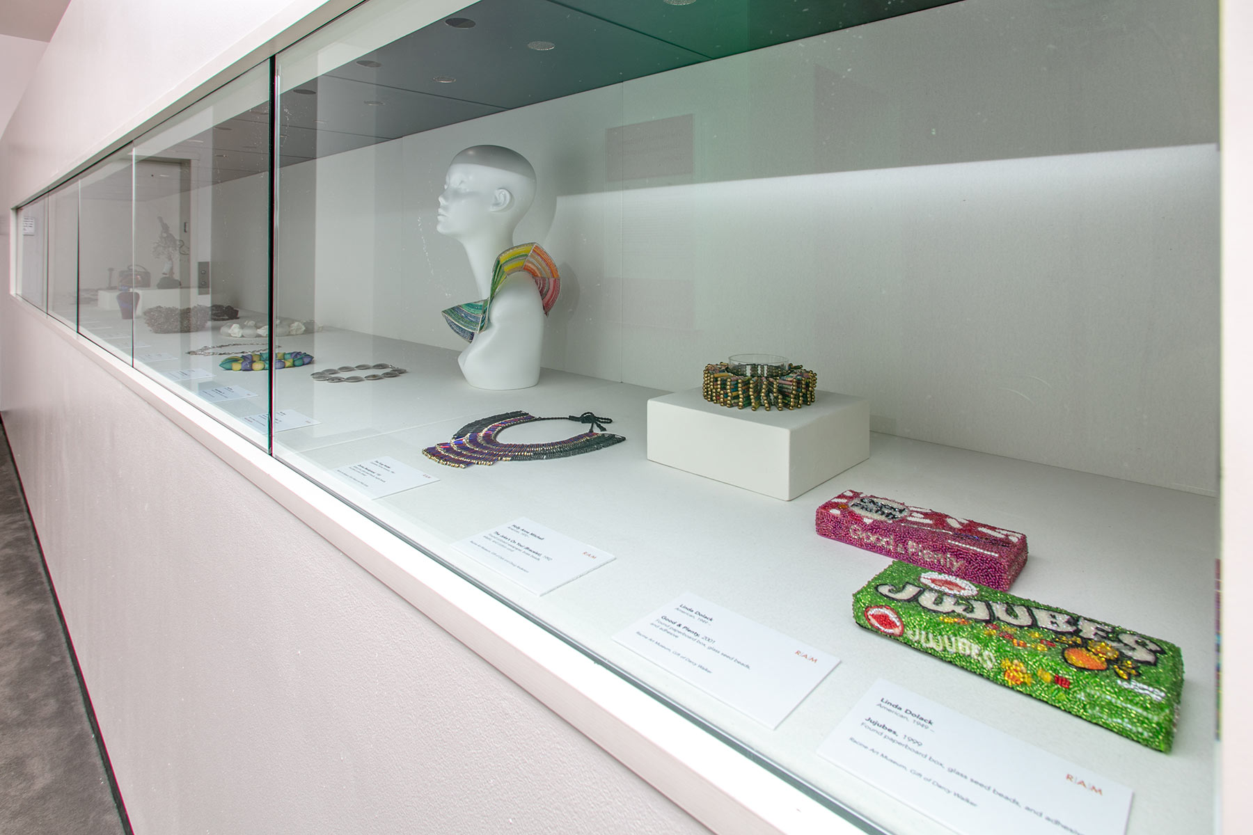 Installation view of the Racine Art Museum exhibition, Get a Bead On. Beaded candy boxes and a mannequin bust can be seen.