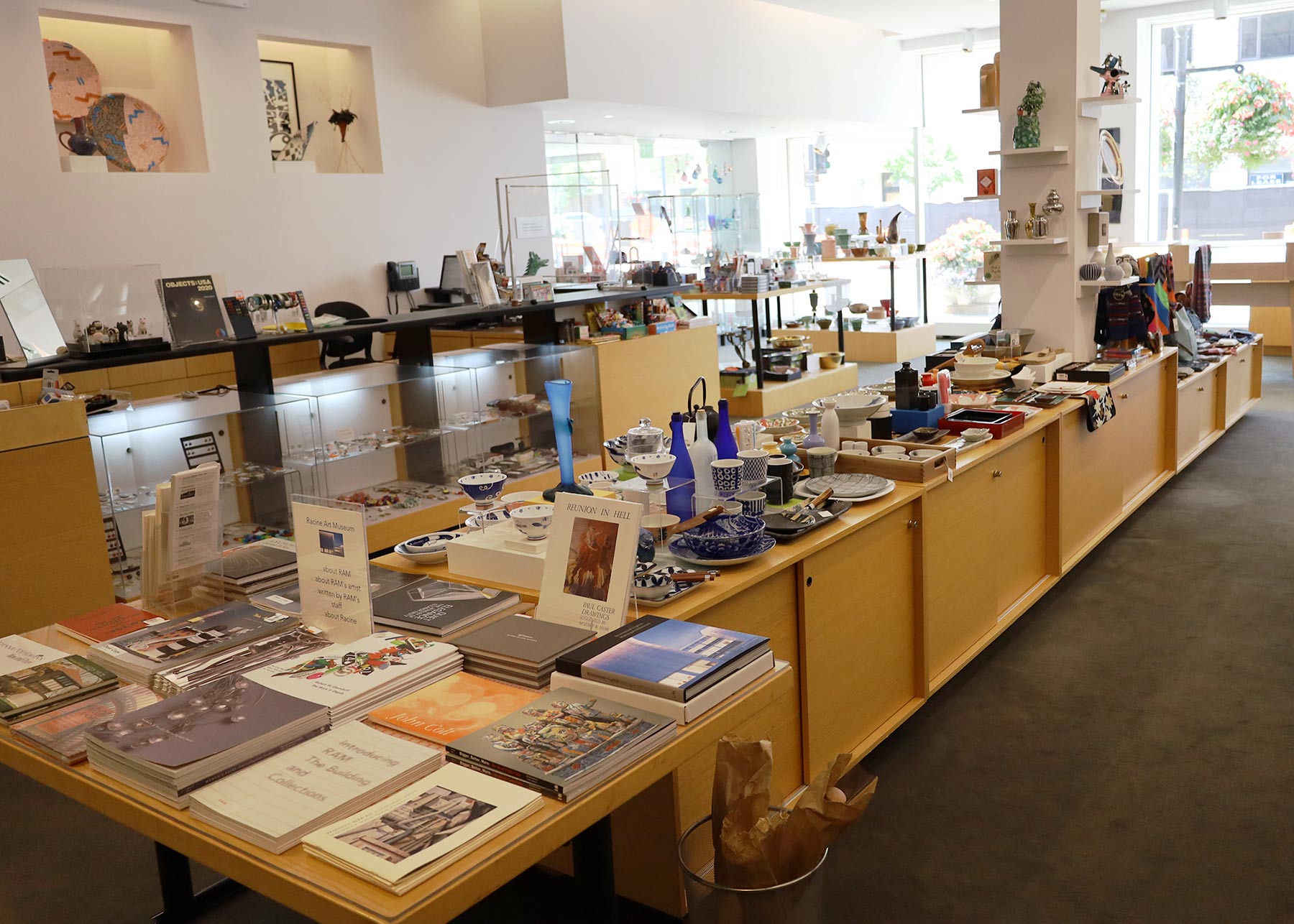 Internal view of the RAM Museum Store focusing on long tables with book stacks and lots of dining ware.