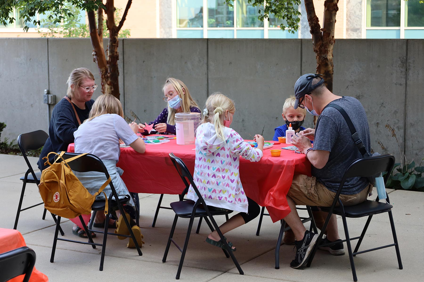 Family of six creating metal repouse stars at a table outside during Free First Friday at RAM